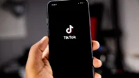 Mão segurando smartphone com o logotipo do TikTok na tela